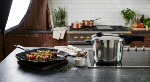 A high-end editorial kitchen setting featuring a sleek cast-iron grill pan and a modern stainless st